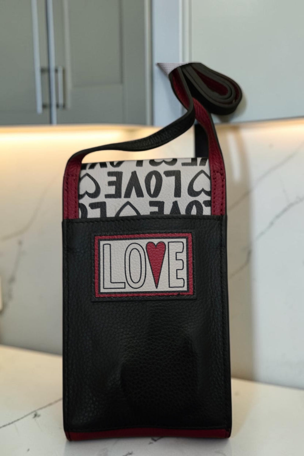The Gettin Place Brighton Look of Love crossbody phone organizer in black, white, and red with heart appliqué.