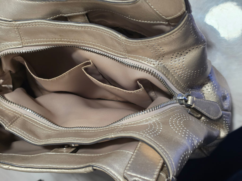 The Gettin Place Coach metallic gold leather hobo bag interior with fabric lining, pockets, and silver zip closure.