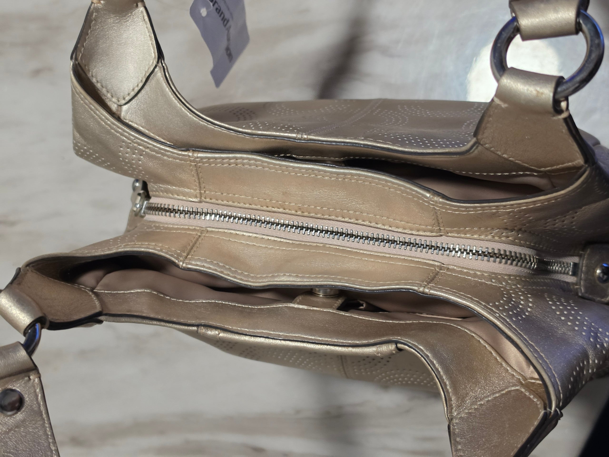 The Gettin Place metallic gold leather Coach shoulder bag with perforated signature pattern and top-zip closure.