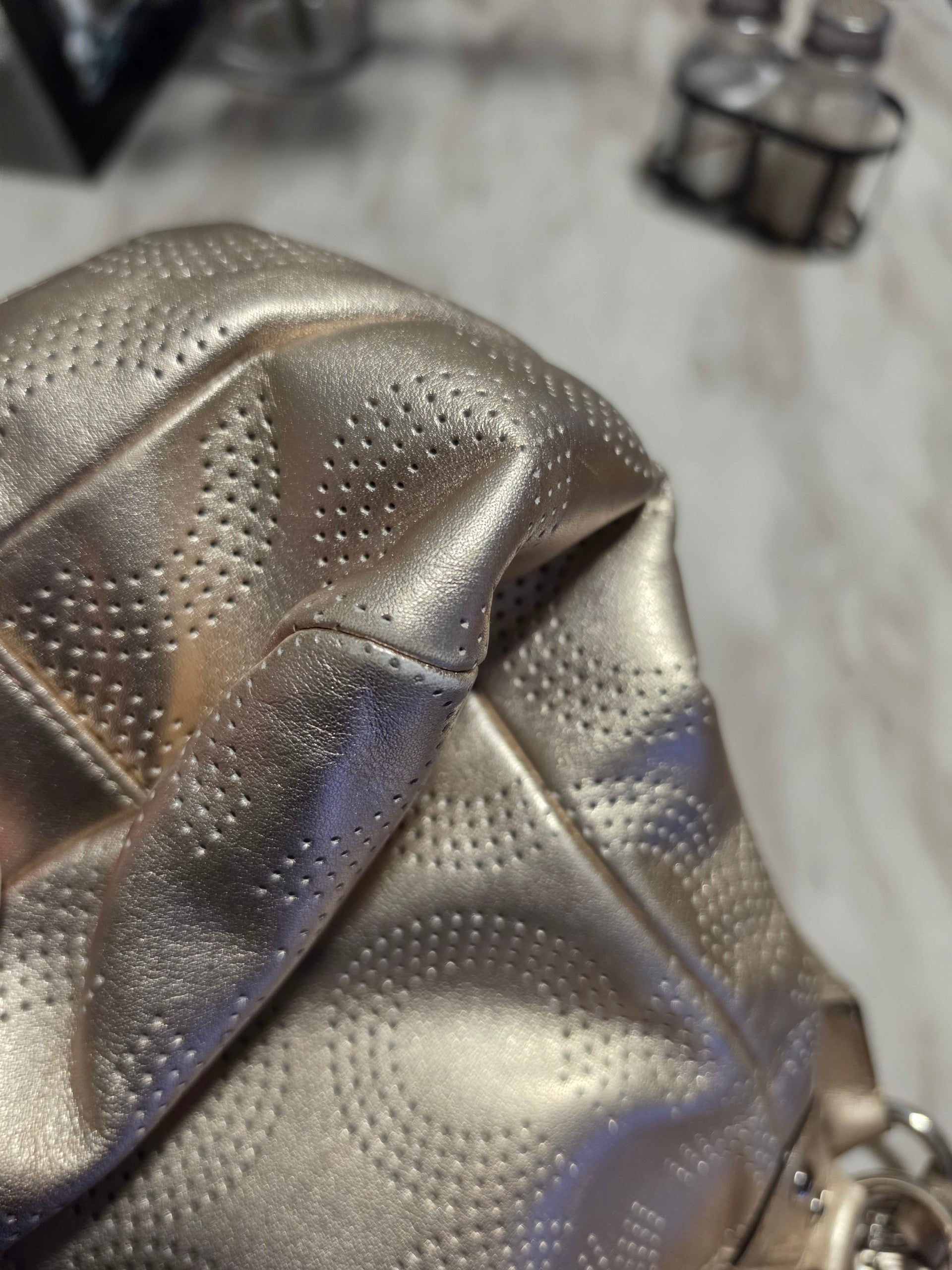 The Gettin Place Coach metallic gold leather hobo bag featuring a detailed perforated signature pattern texture