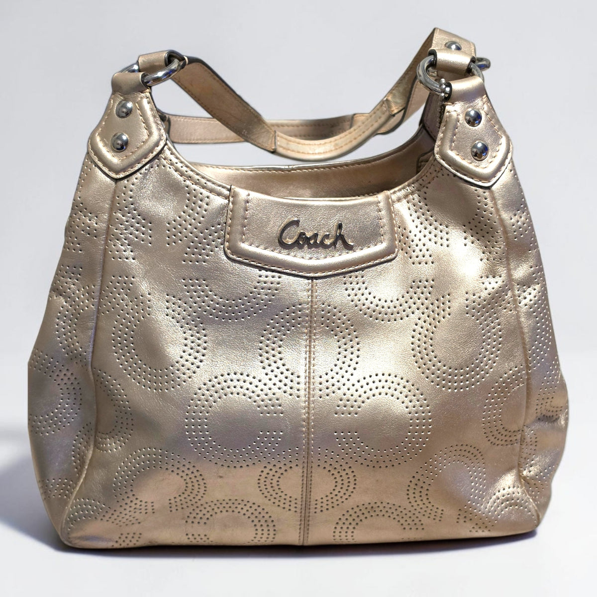 The Gettin Place Coach metallic gold leather hobo bag with perforated signature pattern and silver-tone hardware.