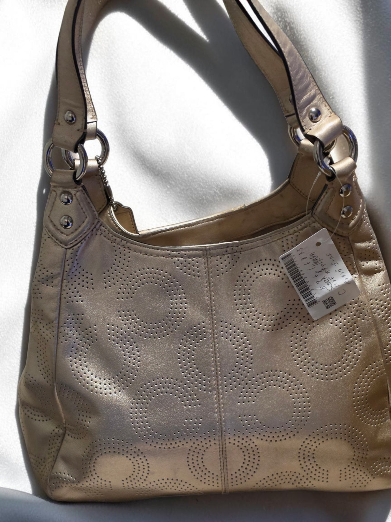The Gettin Place Coach metallic gold leather hobo bag with perforated signature pattern and silver-tone hardware.