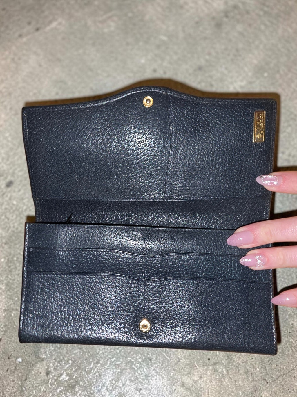 The Gettin Place vintage Gucci navy leather bifold wallet interior with gold-tone plaque on a gold satin background