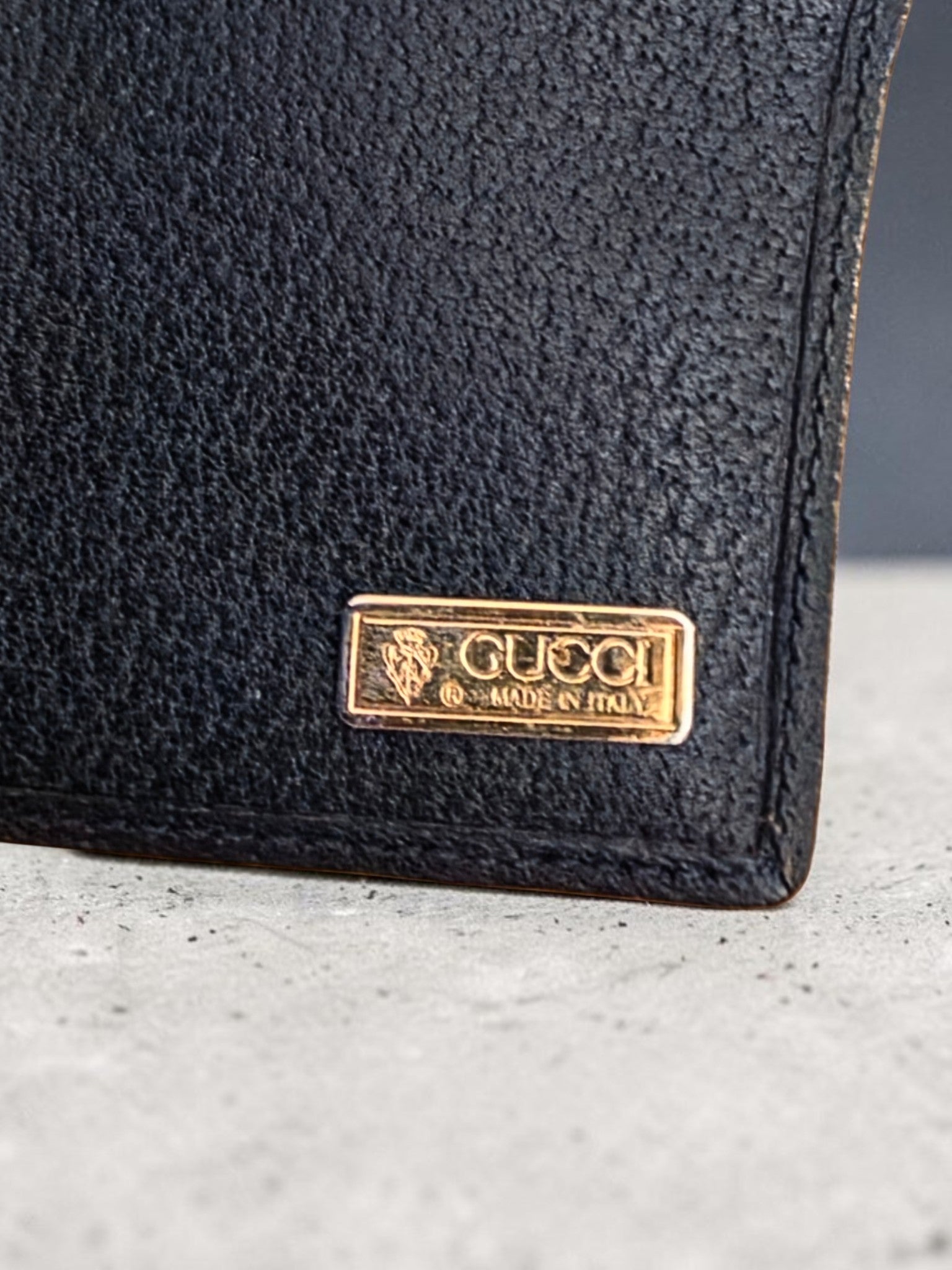 The Gettin Place vintage Gucci bifold wallet featuring navy leather and a gold-tone Gucci Made in Italy metal plaque.