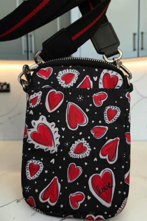 The Gettin Place black crossbody bag with red heart print, featuring a branded LOVE patch and adjustable strap.