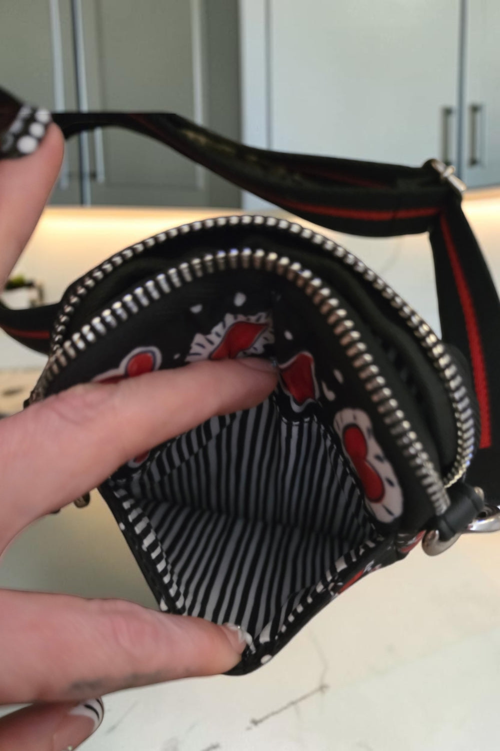 The Gettin Place Brighton crossbody bag interior with black and white striped lining and heart print exterior