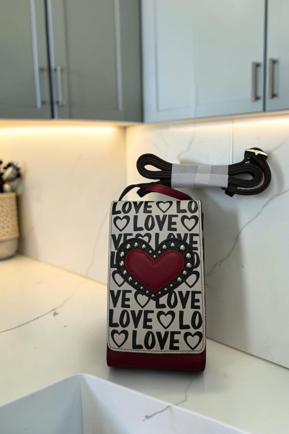 The Gettin Place Brighton Look of Love crossbody phone organizer in black, white, and red with heart appliqué.
