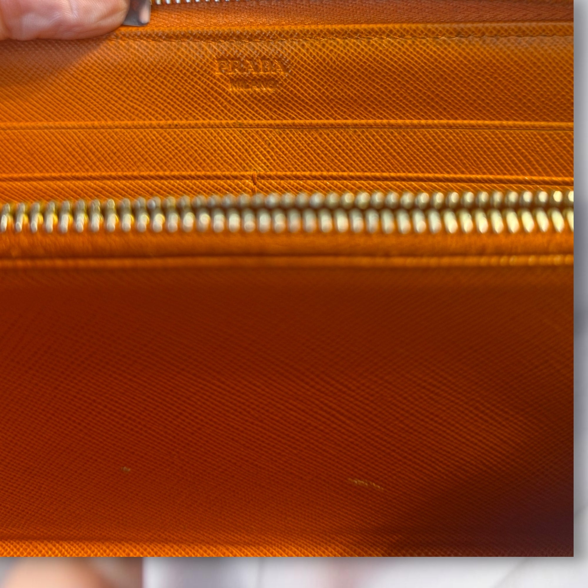 The Gettin Place orange Saffiano leather Prada zip-around wallet interior with gold-tone zipper and embossed logo.