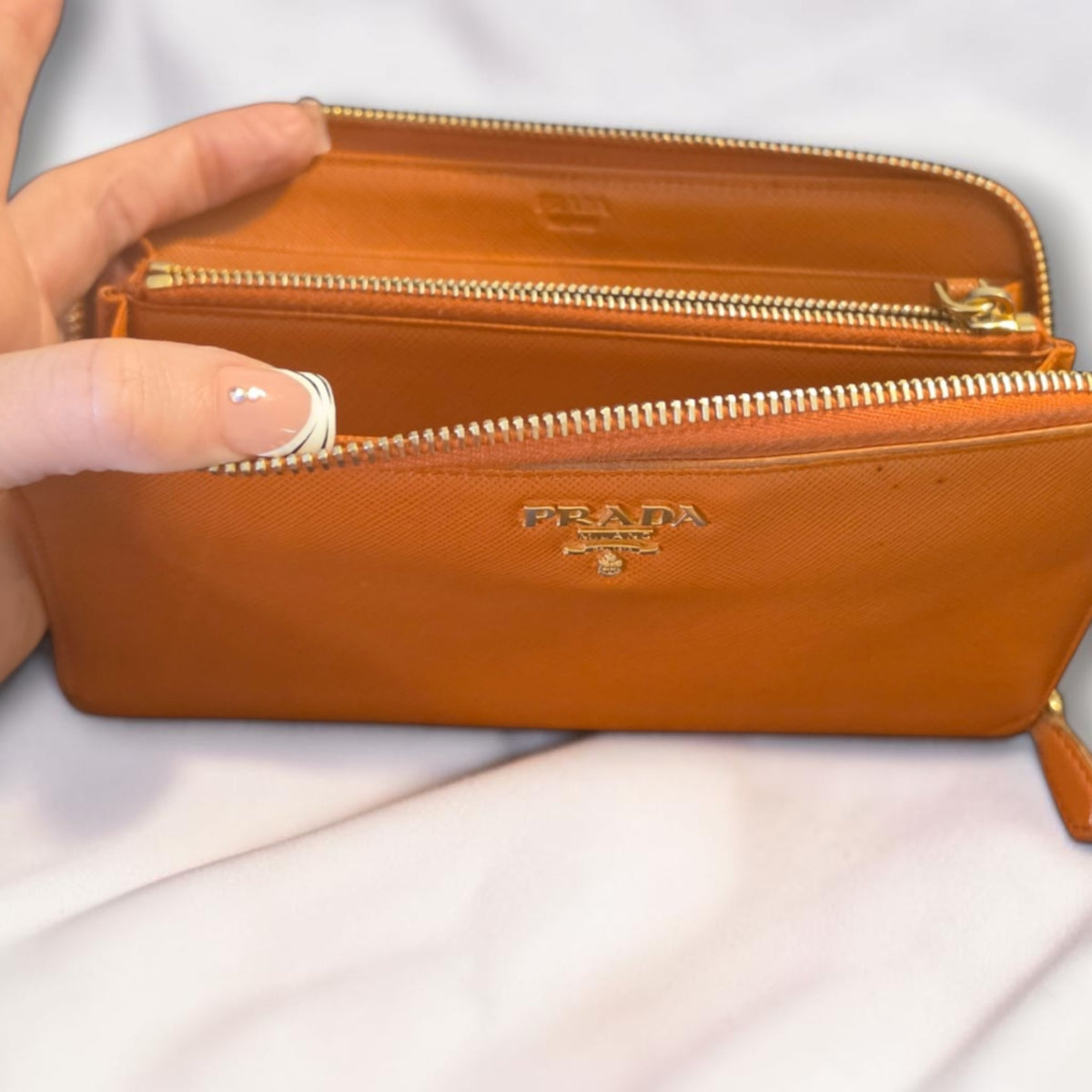 The Gettin Place orange Saffiano leather Prada zip-around long wallet with gold-tone logo plaque and interior pockets.